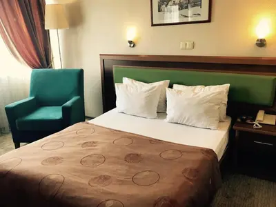 a hotel room with a bed and a green chair at Hotel Villa Marina in Bandırma