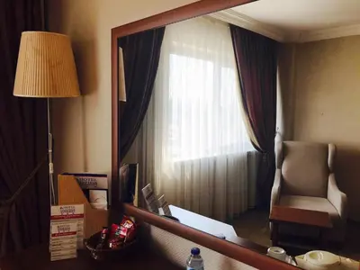 a mirror in a hotel room with a chair and a window at Hotel Villa Marina in Bandırma