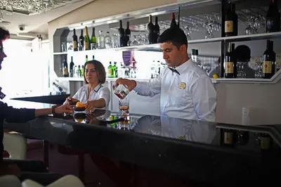 a man standing behind a bar preparing a drink at Hotel Villa Marina in Bandırma