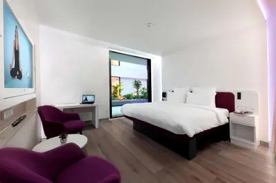 a bedroom with a large bed and a purple chair at YOTELAIR Istanbul Airport, Duty free - International Transit area in Istanbul