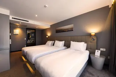 two beds in a hotel room with white sheets at Inncity Hotel Nisantasi in Istanbul