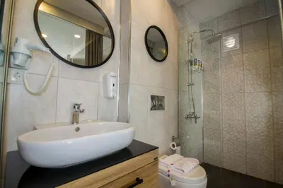 a bathroom with a sink and a shower with a mirror at Hit Suites Avcilar Hotel in Avcılar