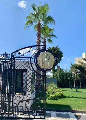 a gate with a clock in front of a palm tree at Istanbul Park Hotel in Tuzla