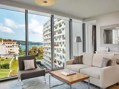 a living room with a couch and a table and windows at The Grand Tarabya Managed by Accor in Istanbul