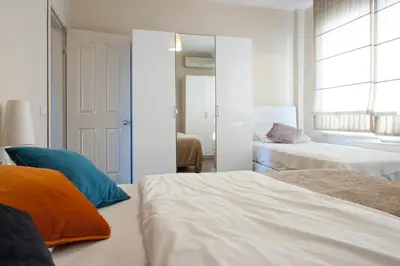 a white bedroom with two beds and a window at Aslan Apartments in Istanbul
