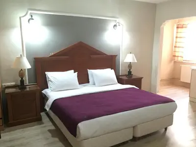 a bedroom with a large bed with purple sheets and white pillows at Elite Hotel City Center Corlu Bed and Breakfast in Corlu