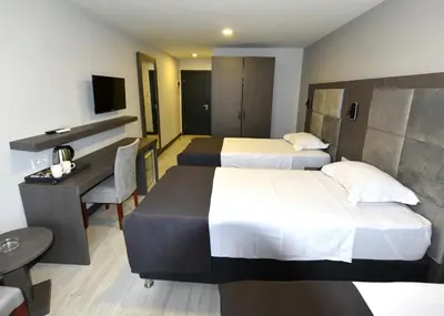 a hotel room with two beds and a desk at Sahil Hotel Pendik in Tuzla