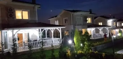 a white house with a porch at night at PALACE KIRKPINAR in Sakarya