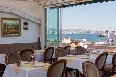 a restaurant with tables and chairs and a large window at Darussaade Hotel Old City - Sultanahmet in Istanbul