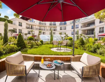 a patio with two chairs and a table with a red umbrella at CVK Park Bosphorus Hotel Istanbul in Istanbul
