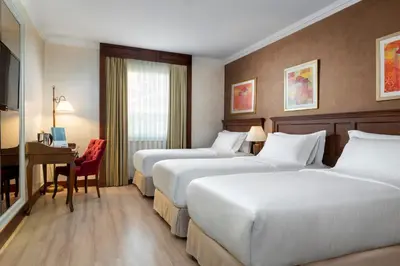 a hotel room with two beds and a desk at Occidental Taksim in Istanbul