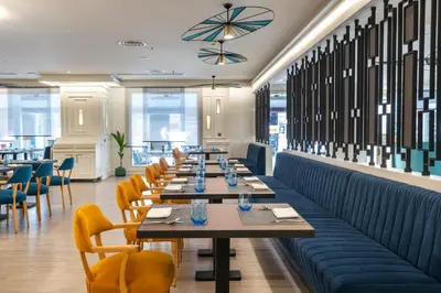 a row of tables in a restaurant with yellow chairs at Occidental Taksim in Istanbul