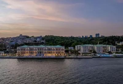 a building on the water in front of a city at Çırağan Palace Kempinski Istanbul in Istanbul