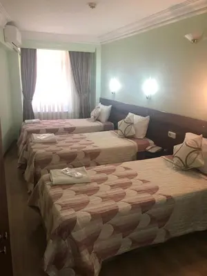 a hotel room with three beds and a couch at Hivas Hotel in Istanbul