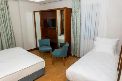 a hotel room with two beds and a chair at Long Stay İstanbul Hotel in Istanbul