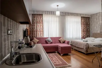 a living room with a pink couch and a bed at My Palace Aırport in Istanbul