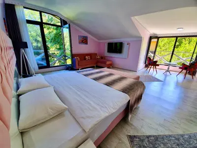 a bedroom with a large bed in a room with windows at Kadifeli Konak Hotel & Bungalow in Kocaeli