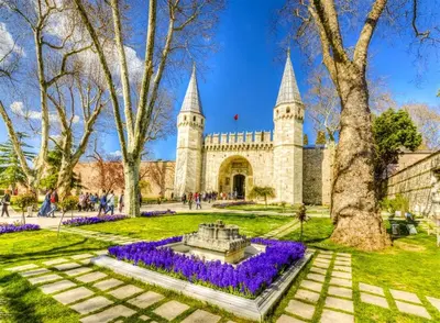a park with a fountain in front of a building with purple flowers at Şehir Hotel Old City in Istanbul