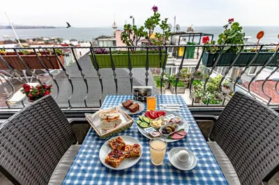 a table with food on top of a balcony with the ocean at Stanpoli Hostel in Istanbul