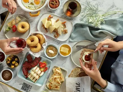 a table topped with plates of food with people eating at Stayso The House Hotel in Istanbul