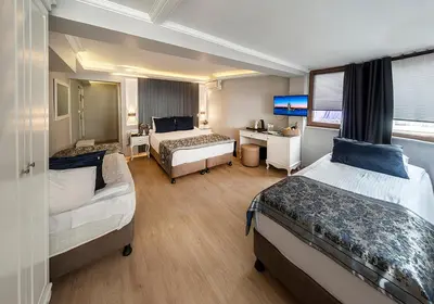 a hotel room with two beds and a desk at Beyazit Palace Hotel in Istanbul