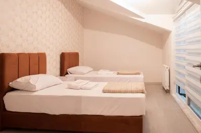a bedroom with two beds with white sheets at Araz Suit in Burgaz