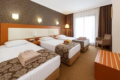 a hotel room with two beds and a chair at Grand Hotel Avcılar in Istanbul