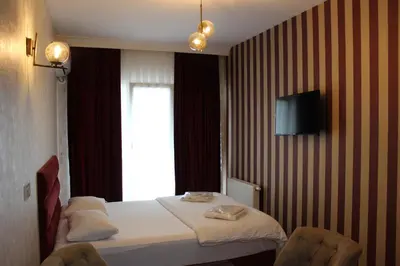 a hotel room with a bed with two chairs and a television at Quars Suite in Esenyurt