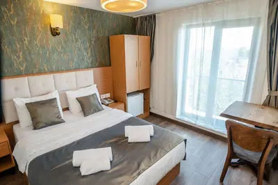 a bedroom with a bed and a desk and a window at The Camelot Hotel in Istanbul