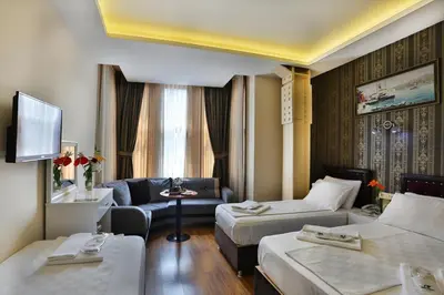 a hotel room with two beds and a couch at Gh Suites Taxim Hotel in Istanbul