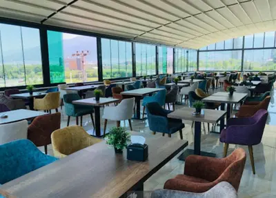 a restaurant with tables and chairs and windows at Grand Rimedya Hotel Bursa in Panayır