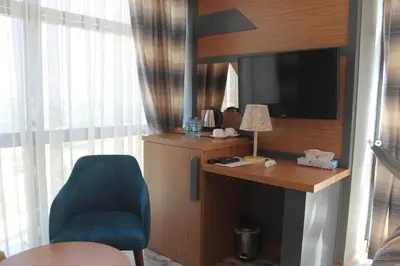 a room with a desk and a chair and a television at Grand Rimedya Hotel Bursa in Panayır