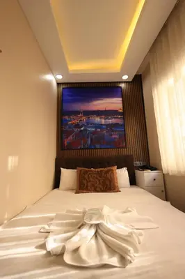 a bedroom with a white bed with a painting on the wall at HamzaBey Hotel in Istanbul