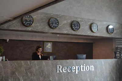 a woman in an office with clocks on the wall at Marina Park Hotel in Istanbul