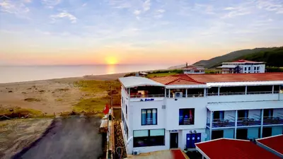 a white building with a sunset in the background at Yalıköy Deniz Otel Istanbul in Yalıköy