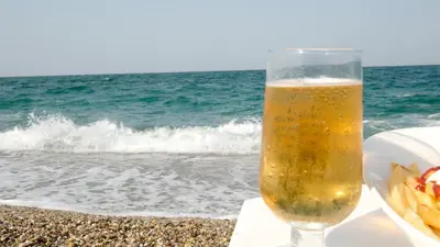 a glass of beer sitting next to the beach at Yalıköy Deniz Otel Istanbul in Yalıköy