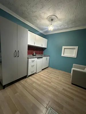 an empty kitchen with white cabinets and a wooden floor at Ada Apart Hotel in Istanbul