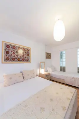 a white bedroom with two beds and a window at Istanbul Amedros Home in Istanbul