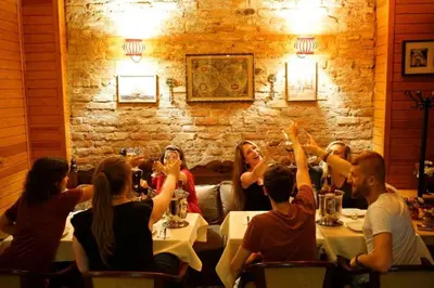 a group of people sitting at a table with their hands in the air at Cheers Lighthouse in Istanbul