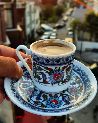a person holding a cup of coffee on a plate at Rose Bouquets Hotel in Istanbul