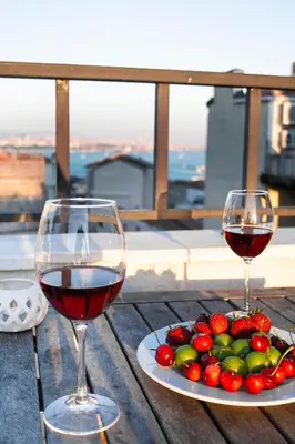 two glasses of wine and a plate of fruit on a table at Maravilloso Hotel Galata in Istanbul