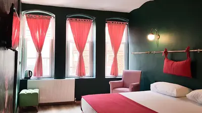 a bedroom with red curtains and a bed and a chair at Casa Rosa Suites in Istanbul