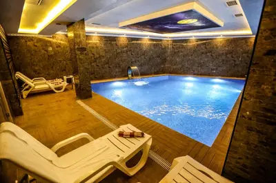 a large swimming pool with two lounge chairs and a table at Thermal Saray Hotel & Yalova in Gokcedere