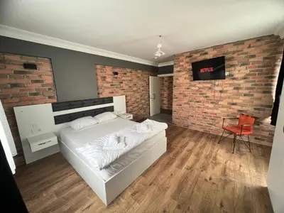 a bedroom with a white bed and a brick wall at Karaca Suite in Tuzla