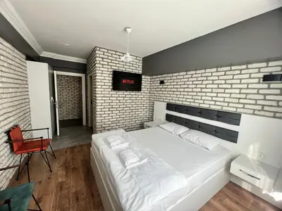 a bedroom with a white bed and a brick wall at Karaca Suite in Tuzla
