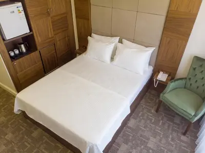 a bedroom with a white bed and a green chair at Bursa Ulupark Hotel in Bursa