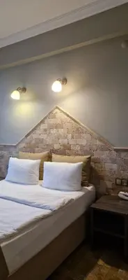 a bed with white pillows and a brick wall at Royal Park Hotel Corlu Bed and Breakfast in Tekirdag