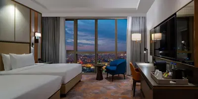a bedroom with a bed and a desk and a large window at Hilton Mall Of Istanbul in Istanbul