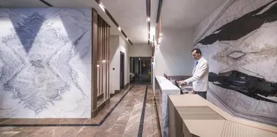a man standing in a room with a marble wall at MENALO HOTEL PREMIUM ISTANBUL AIRPORT in Istanbul