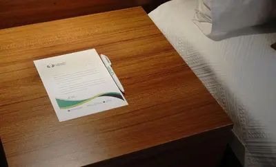 a paper on top of a wooden table next to a bed at Class Hotel Bosphorus With Jacuzzi in Istanbul
